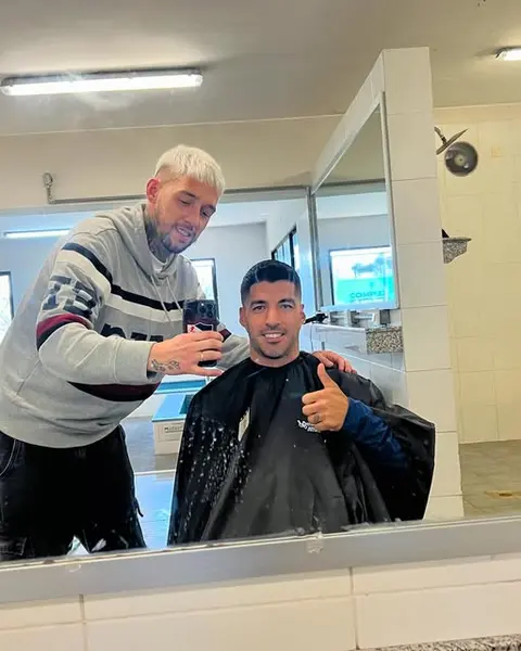 Barbero fotografiando el resultado de un corte frente al espejo