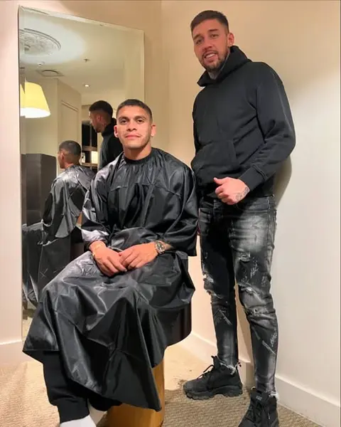 Barbero de pie junto a un cliente con capa de corte