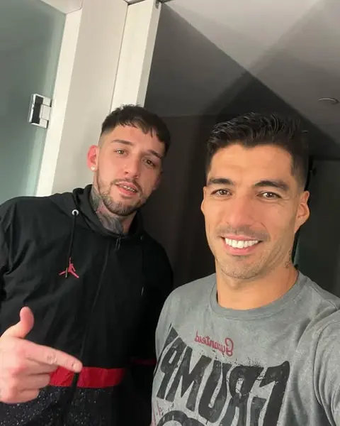 Selfie del barbero con un cliente sonriendo